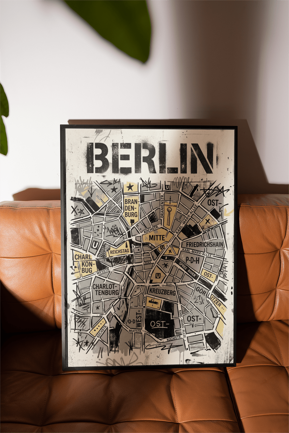 Framed Berlin City Map wall art of an abstract map in black and beige on a tan leather sofa