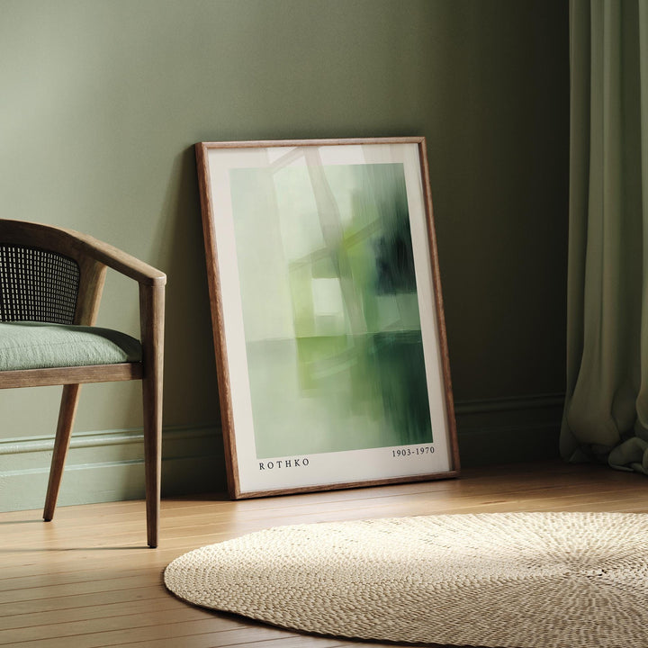 Print leaning on the floor with olive green abstract shapes beside a chair with a green cushion