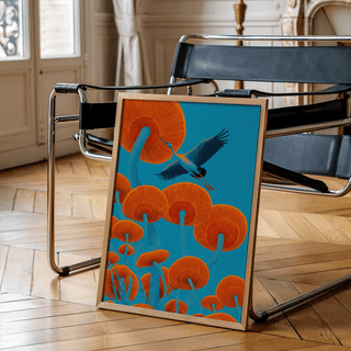 Print leaning on a black chair featuring Japandi Bird Print with orange mushrooms and blue crane in minimalist style