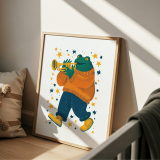 Print leaning on a floor next to a cushion with a frog playing trumpet in orange and blue