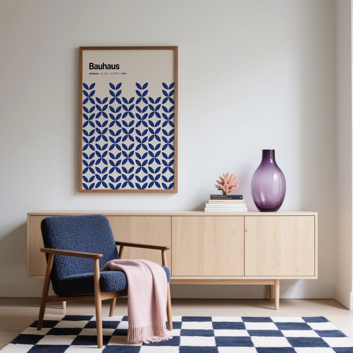 Simple wall art with blue geometric Bauhaus pattern hanging above a light wood sideboard with a purple vase