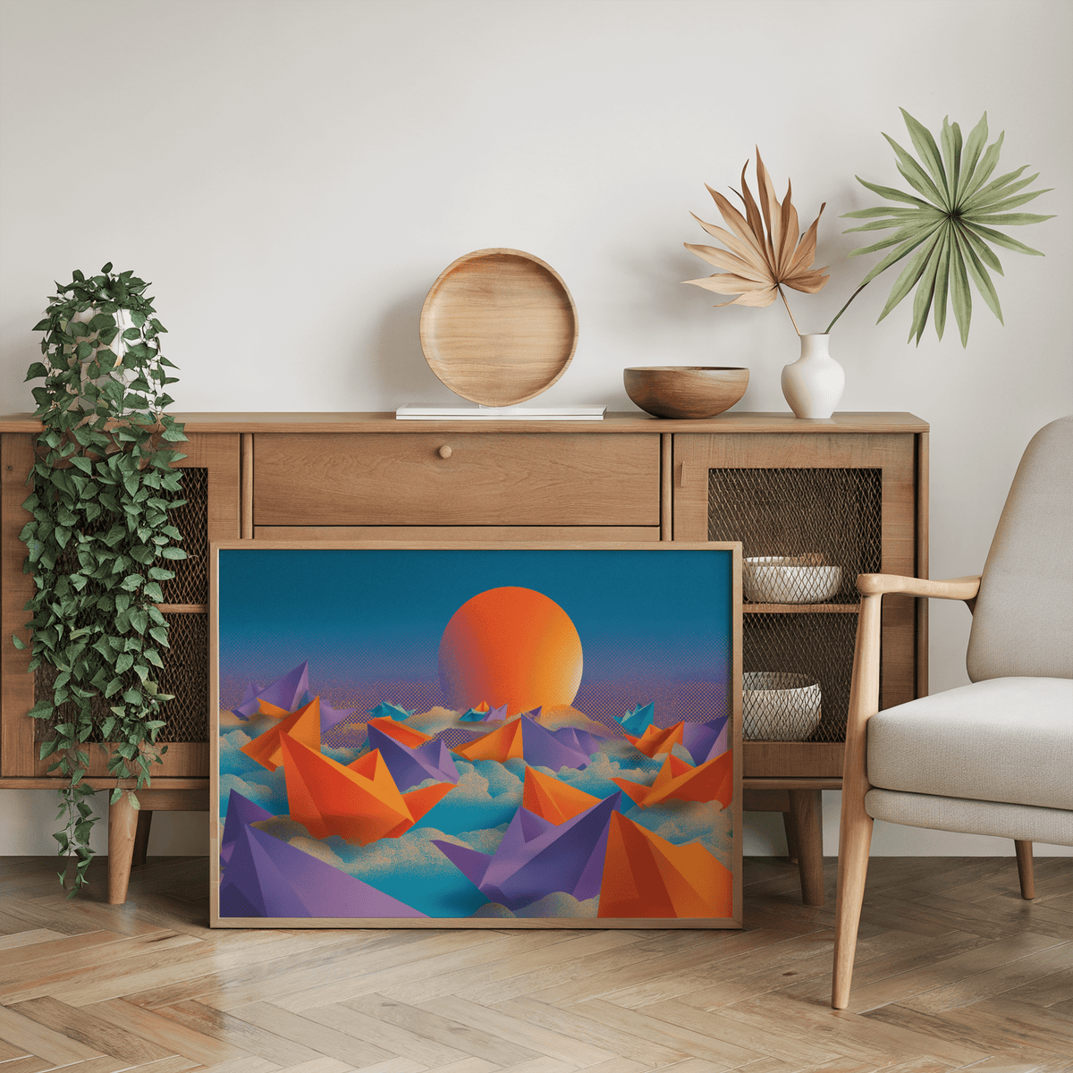 Origami wall art leaning on a wooden sideboard with orange and purple boats and an orange sun with green plant
