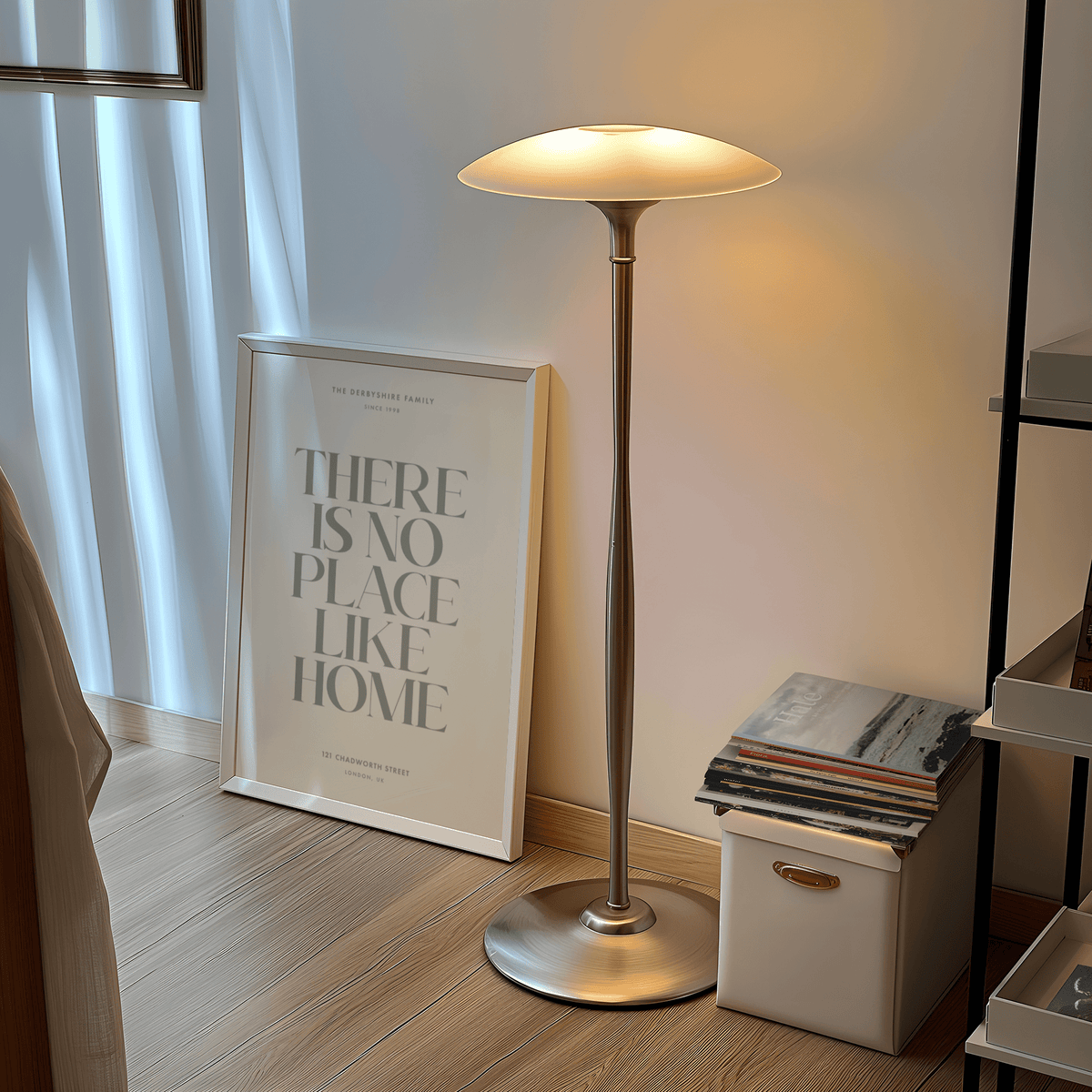 No Place Like Home print leaning on wooden floor near a lit silver floor lamp and small storage box