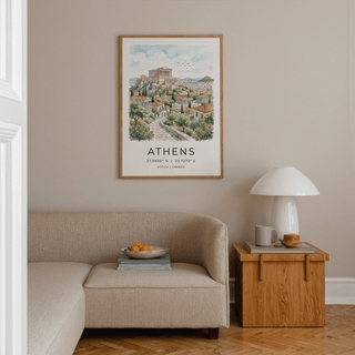 Athens art print in watercolour style hangs above a beige sofa next to a small wooden side table with a lamp