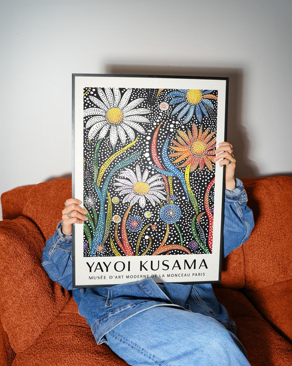 Framed Flower Print for Framing with polka dot flowers in bright colours held on a brown sofa