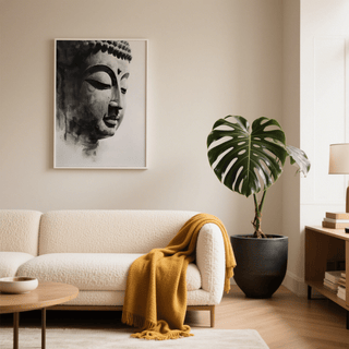 Buddha Art Print in calm monochrome above a sofa with a yellow throw and a large green plant