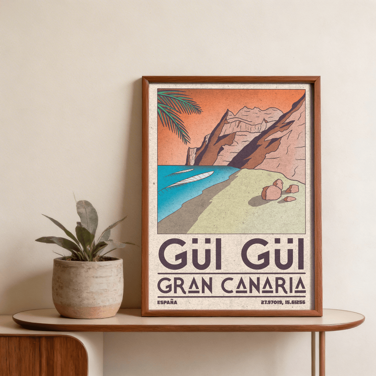Framed Gran Canaria Beach Art Print with orange sky and blue sea on a wooden table with a plant pot