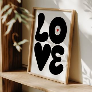 Framed Love Art Print with black letters and small red heart leaning on a wooden shelf