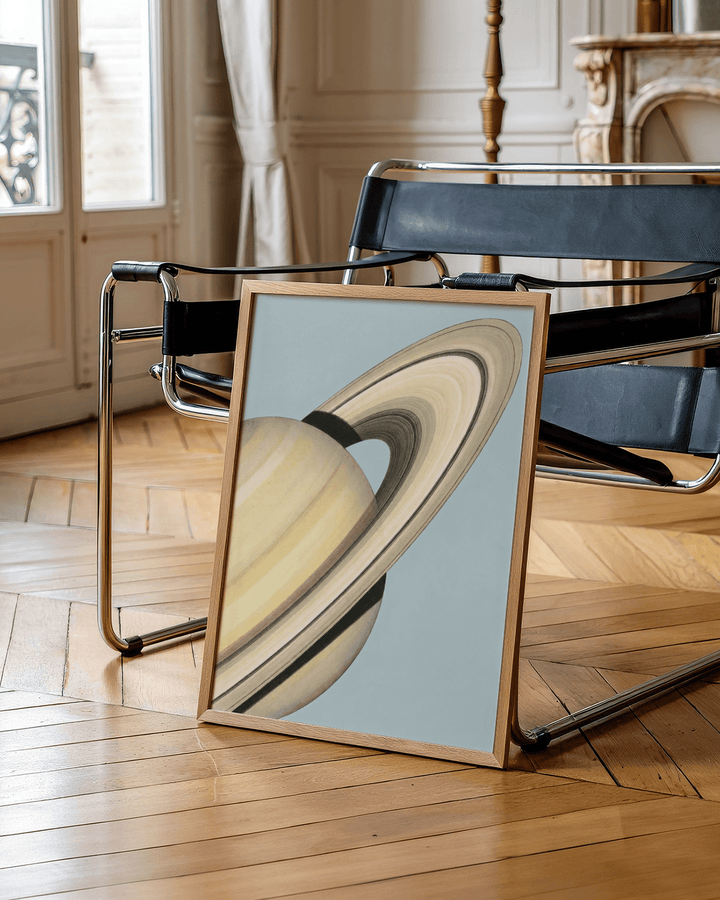 Saturn wall art print leaning on a black metal chair with wooden floor background