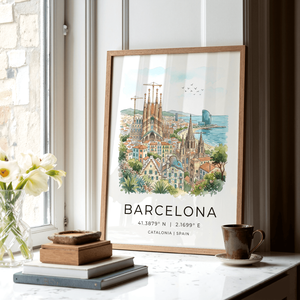 Barcelona watercolor poster leaning on a windowsill beside brown mug and books in soft light
