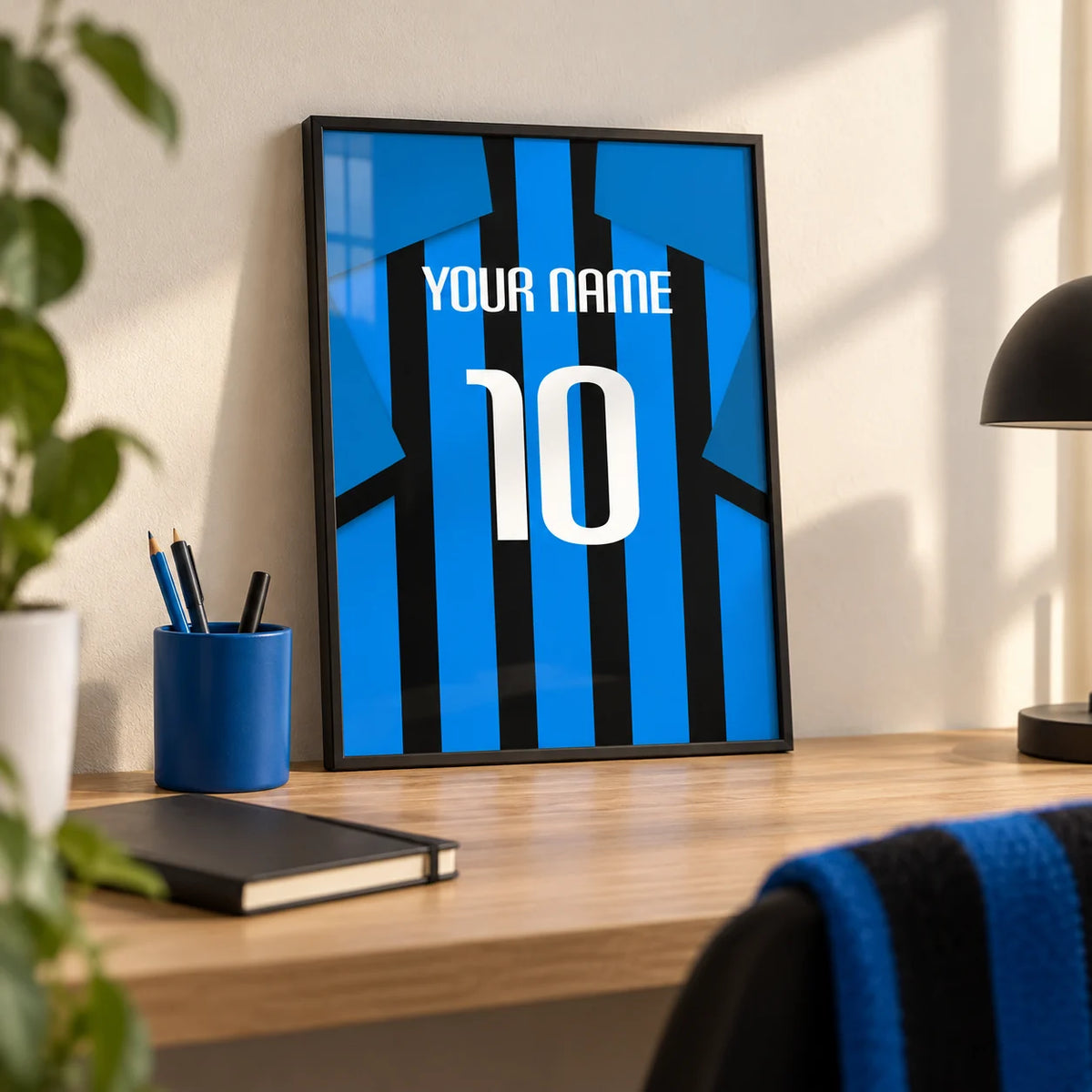 Football Shirt Poster in Black and Blue Stripes with Blue Sleeves, a small A4 framed print leaning on a pale oak desk