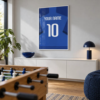 Football Shirt Poster in Blue with Dark Blue Sleeves and White Number, framed on the wall of a clean modern games room in a UK family home with a pale grey wall and oak flooring in a living room