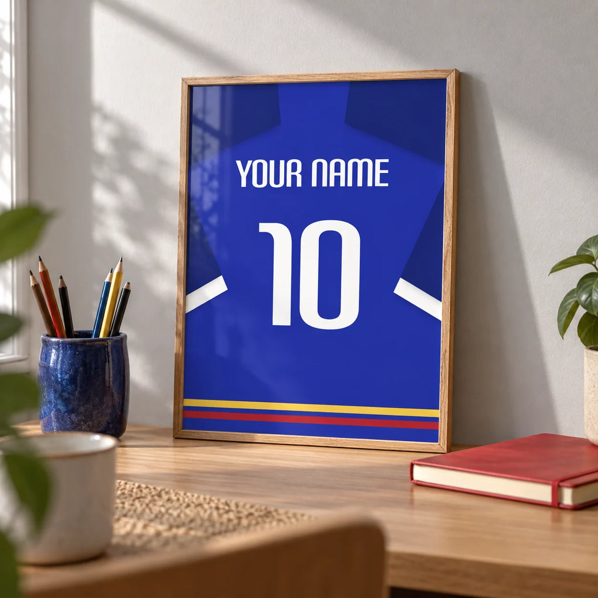Football Shirt Poster in Blue with White Sleeve Stripe, a small A4 framed print leaning on an oak desk