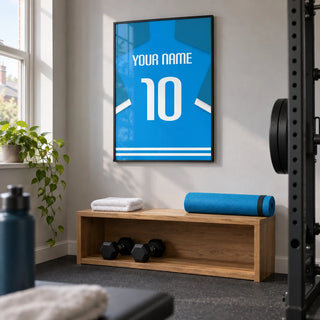 Football Shirt Poster in Bright Blue with White Number, framed on the wall of a compact home gym in a UK terrace with a light grey wall and plain dark rubber flooring