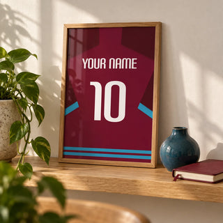 Football Shirt Poster in Claret with Light Blue Sleeve Trim, a small A4 framed print leaning on an oak shelf in a living room