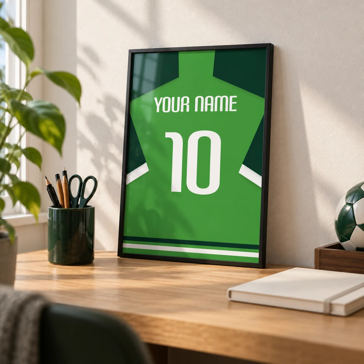 Football Shirt Poster in Green with Dark Green Sleeves, a small A4 framed print leaning on a pale oak desk