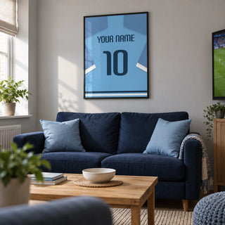 Football Shirt Poster in Light Blue with Dark Blue Number, framed on the wall of a modern football-viewing snug in a UK terraced house with a pale grey wall in a living room