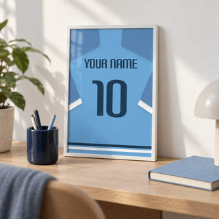 Football Shirt Poster in Light Blue with Dark Blue Number, a small A4 framed print leaning on a pale oak desk