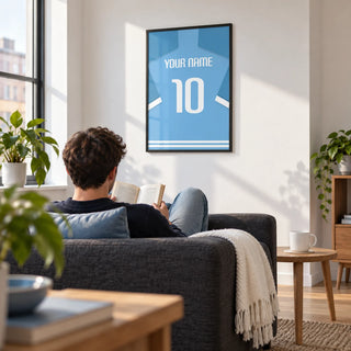 Football Shirt Poster in Light Blue with White Number, framed on the wall of a bright living room in a football fan's first flat (22-28) with a white wall and pale oak floor