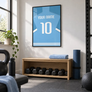 Football Shirt Poster in Light Blue with White Number, framed on the wall of a compact home gym in a converted UK spare room with a white wall and charcoal rubber floor