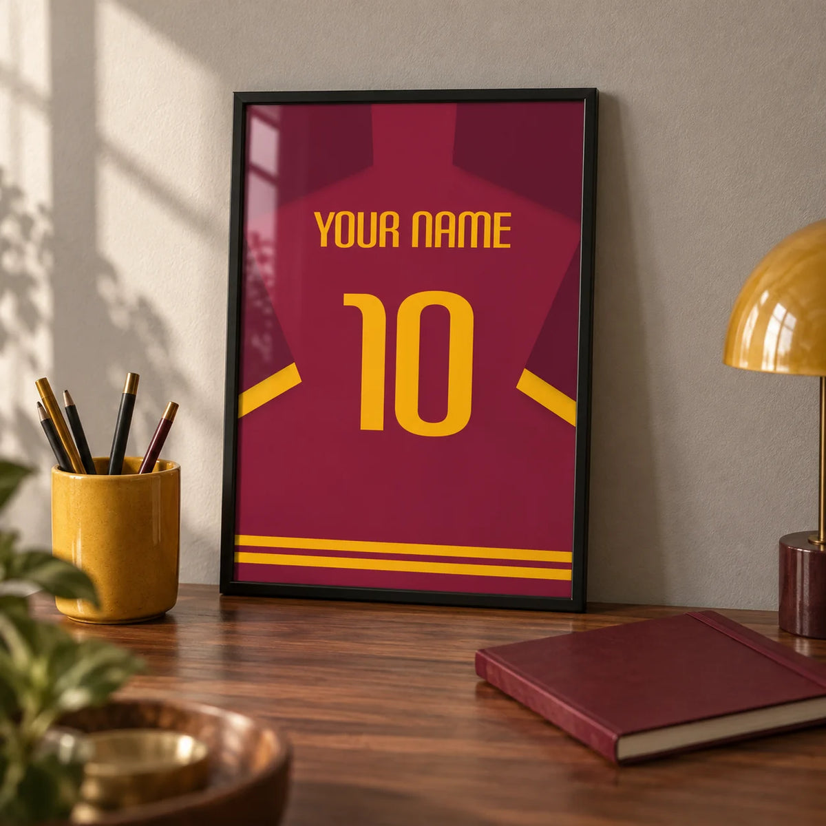 Football Shirt Poster in Maroon with Yellow Number, a small A4 framed print leaning on a walnut desk