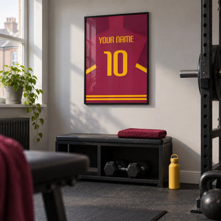 Football Shirt Poster in Maroon with Yellow Number, framed on the wall of a small converted spare-room home gym in a UK terraced house with a pale grey wall and plain rubber flooring
