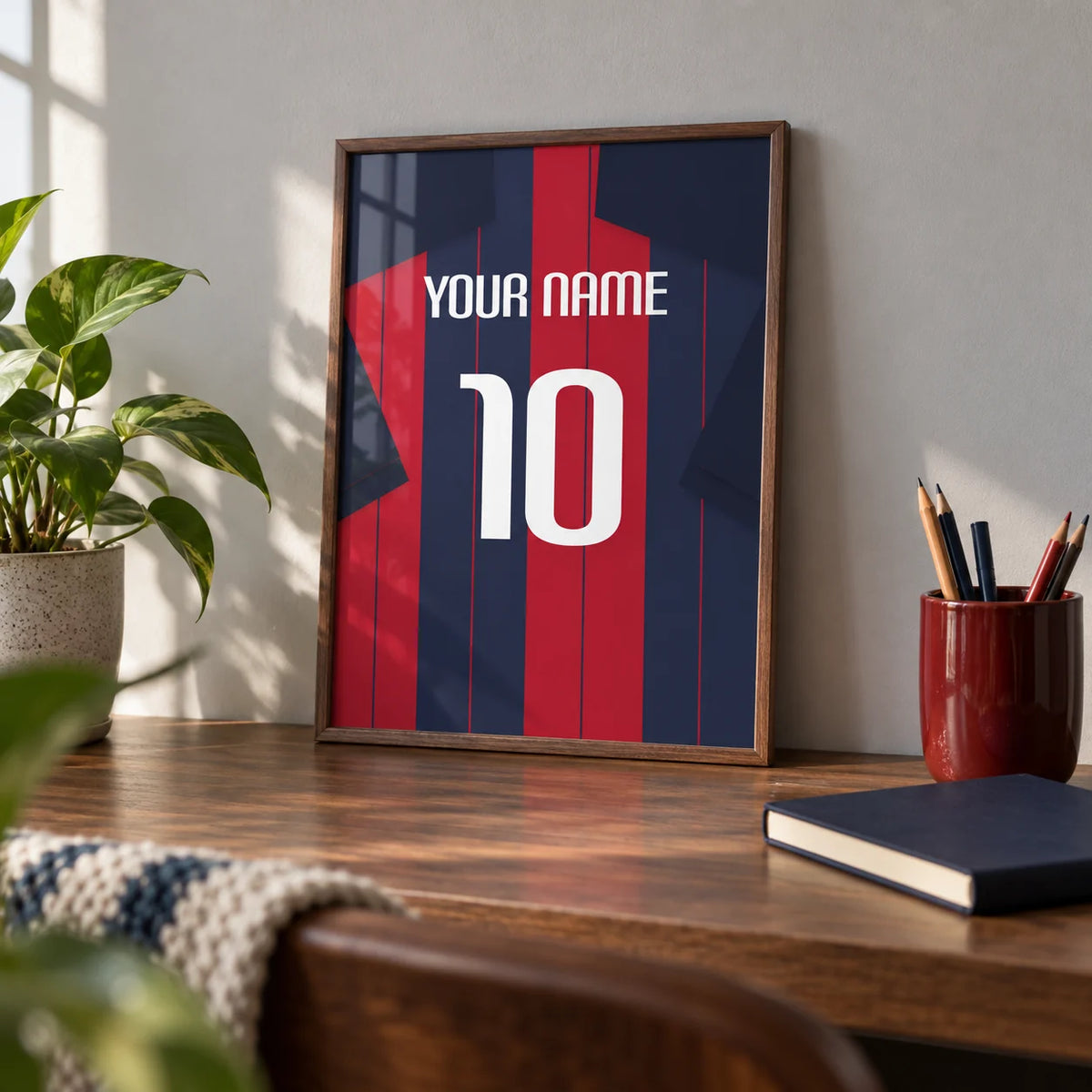 Football Shirt Poster in Navy and Red Stripes, a small A4 framed print leaning on a walnut desk