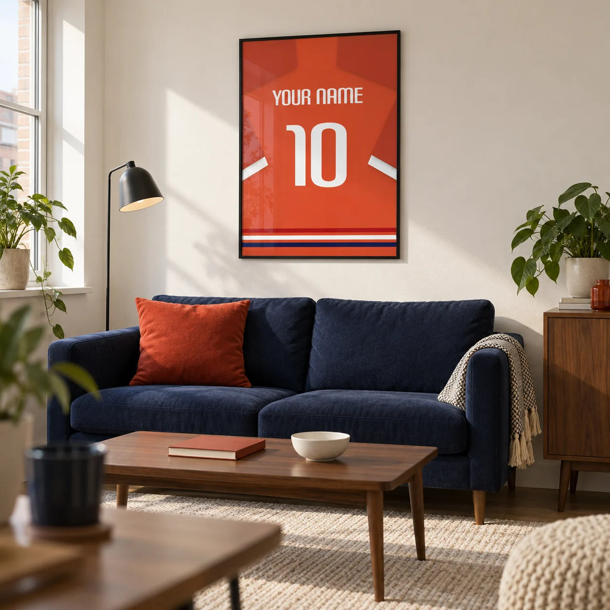 Football Shirt Poster in Orange-Red with White Number, framed on the wall of a crisp living room in a football fan's first UK flat (22-28) with a warm white wall and walnut furniture