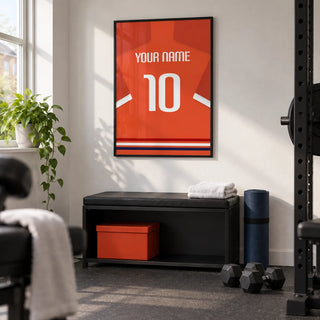 Football Shirt Poster in Orange-Red with White Number, framed on the wall of a modest home gym in a converted UK spare room with white walls and plain charcoal rubber flooring