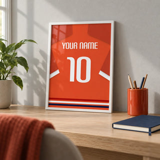 Football Shirt Poster in Orange-Red with White Number, a small A4 framed print leaning on a pale oak desk