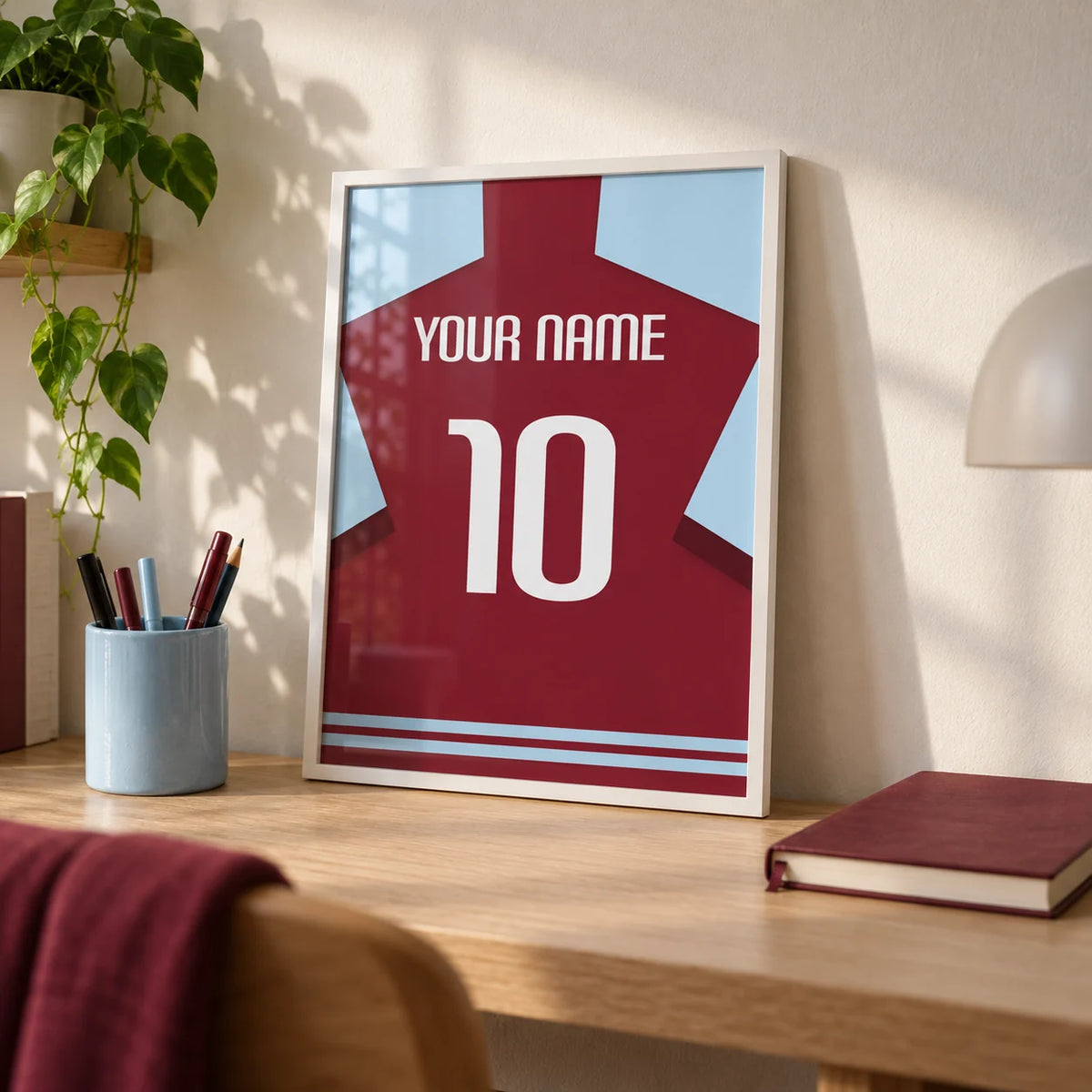 Football Shirt Poster in Plain Claret with White Number, a small A4 framed print leaning on a pale oak desk