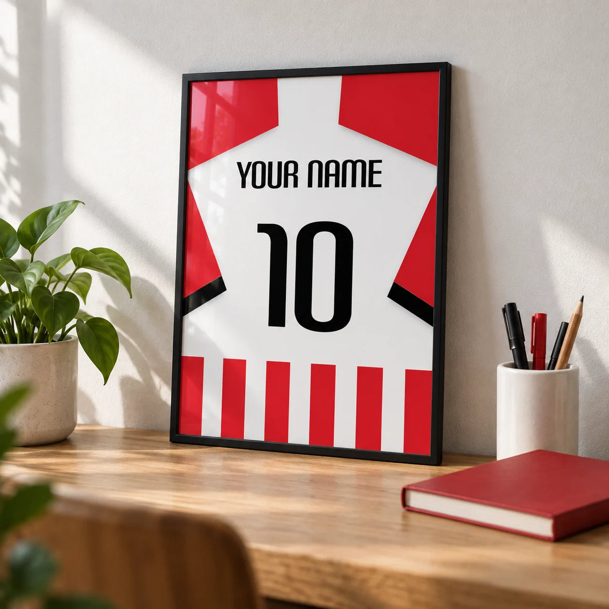 Football Shirt Poster in Red and White Stripes with Black Number, a small A4 framed print leaning on an oak desk