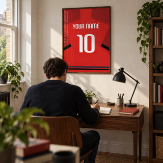 Football Shirt Poster in Red with Black Sleeve Bands, framed on the wall of a compact home study in a UK terrace with an off-white wall