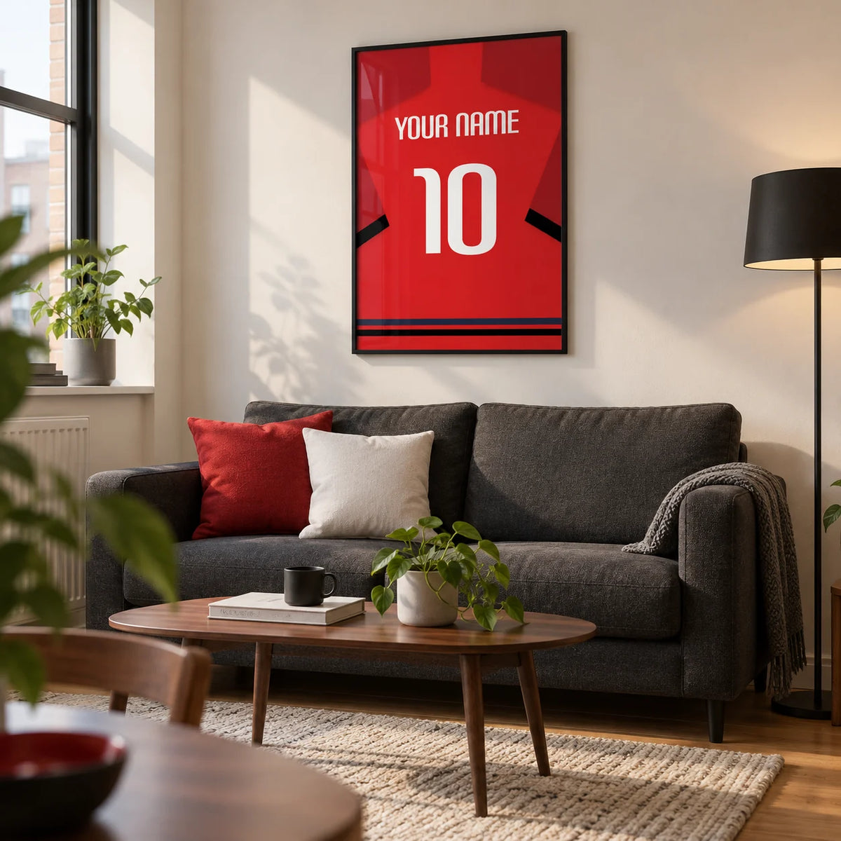 Football Shirt Poster in Red with Black Sleeve Bands, framed on the wall of a contemporary living room in a football fan's first UK flat (22-28) with a warm white wall and oak floor