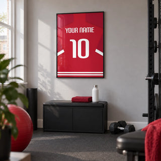Football Shirt Poster in Red with Bold White 10, framed on the wall of a compact home gym in a UK terraced house with a light grey wall and plain charcoal rubber flooring
