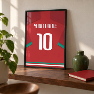 Football Shirt Poster in Red with Green Sleeve Stripe, a small A4 framed print leaning on a walnut shelf in a living room