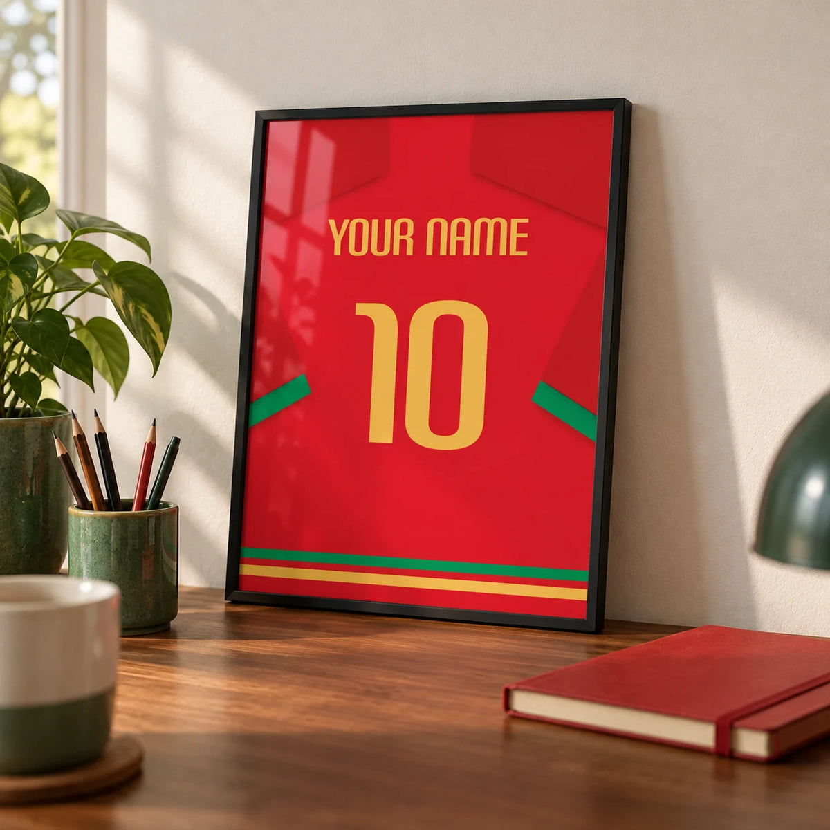 Football Shirt Poster in Red with Green Trim and Yellow Number, a small A4 framed print leaning on a walnut desk