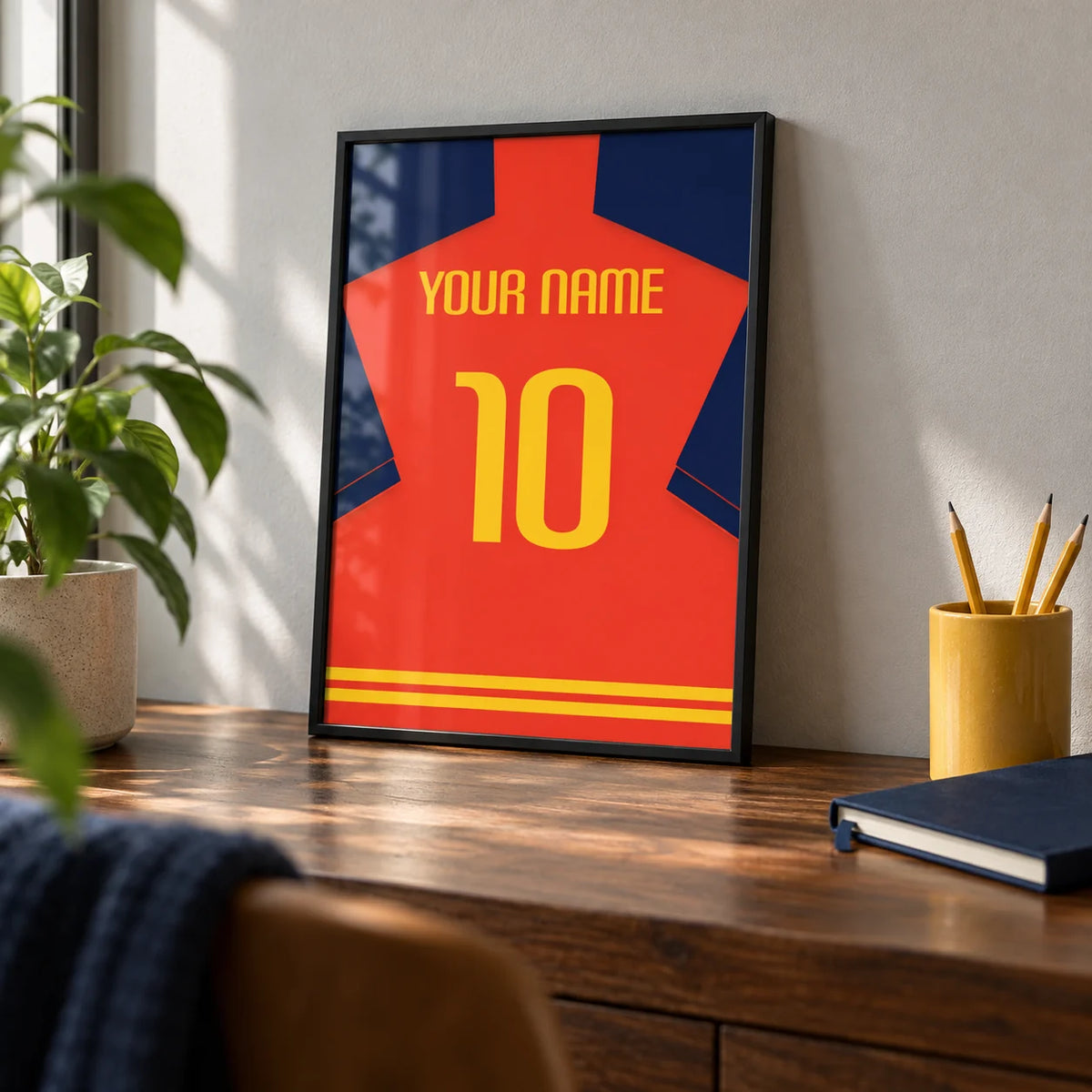 Football Shirt Poster in Red with Navy Sleeves and Yellow Number, a small A4 framed print leaning on a walnut desk