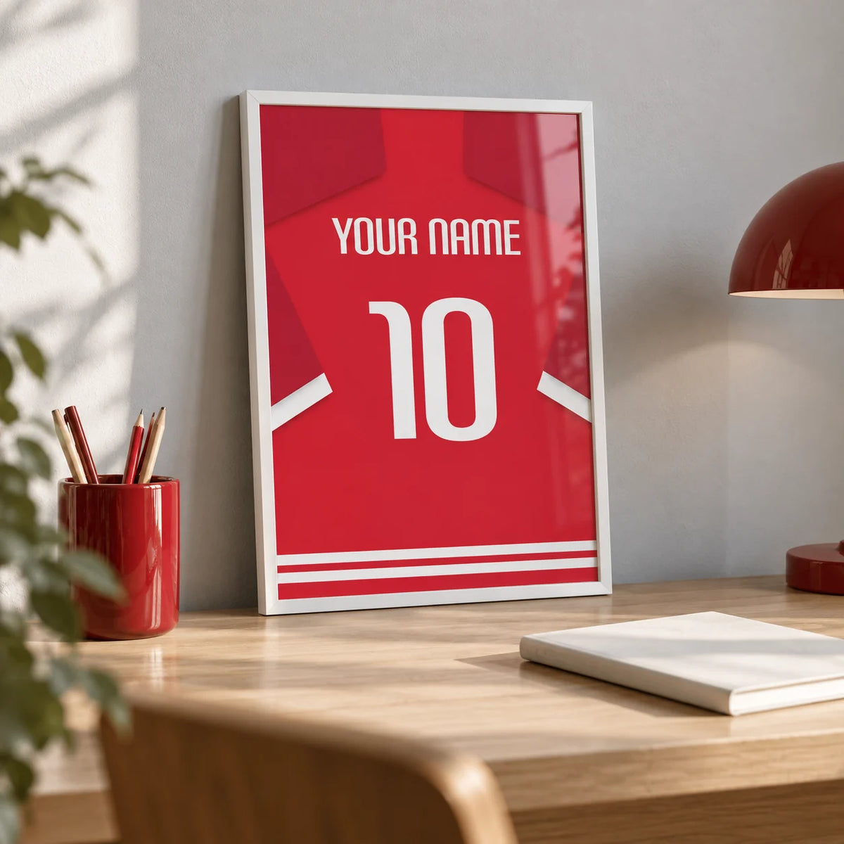 Football Shirt Poster in Red with White Number, a small A4 framed print leaning on a pale oak desk