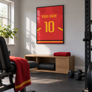 Football Shirt Poster in Red with Yellow Number and Sleeve Stripe, framed on the wall of a small home gym in a converted UK spare room with light grey walls and plain dark rubber flooring