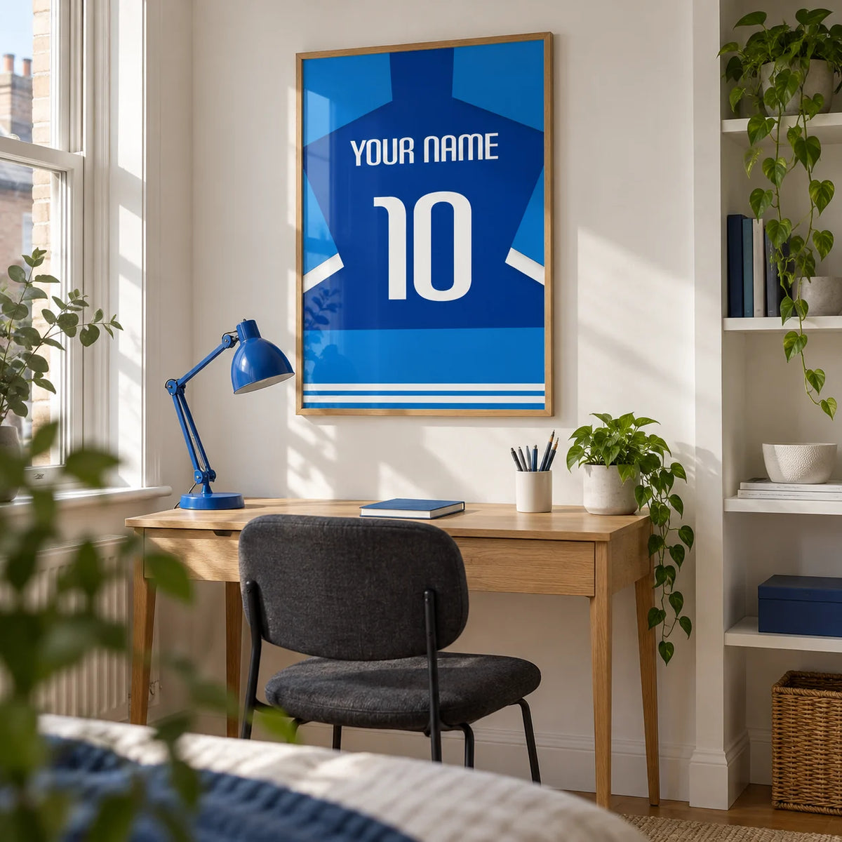 Football Shirt Poster in Two-Tone Blue with White Sleeve Stripes, framed on the wall of a bright home study in a young adult's UK terraced house with a white wall and a built-in alcove