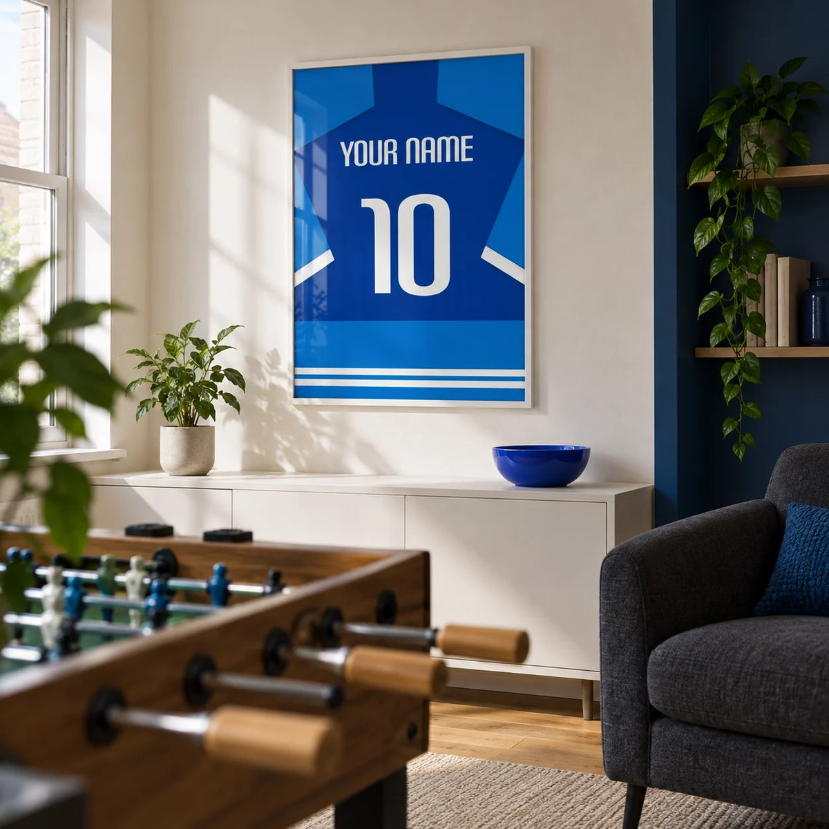 Football Shirt Poster in Two-Tone Blue with White Sleeve Stripes, framed on the wall of a modern football fan's games snug in a UK terrace with a warm white wall and a deep blue painted alcove in a living room