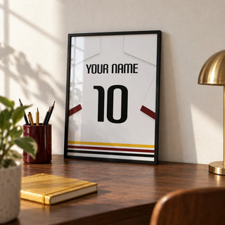 Football Shirt Poster in White with Black Red and Gold Hem Stripes, a small A4 framed print leaning on a walnut desk