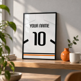 Football Shirt Poster in White with Black Sleeve Bands, a small A4 framed print leaning on an oak shelf in a living room