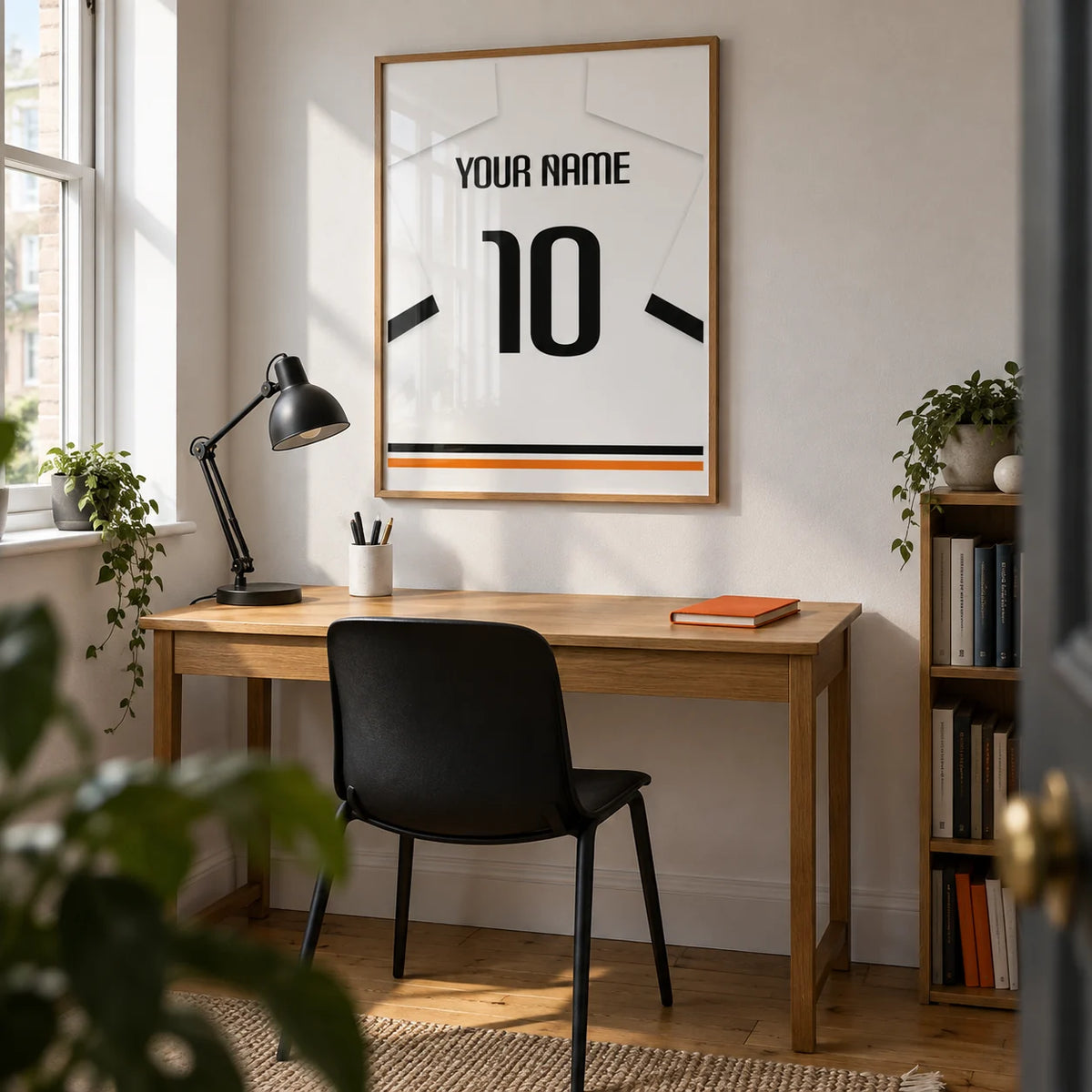 Football Shirt Poster in White with Black Sleeve Bands, framed on the wall of a young adult football fan's compact home office in a UK terrace with a white wall and oak floorboards