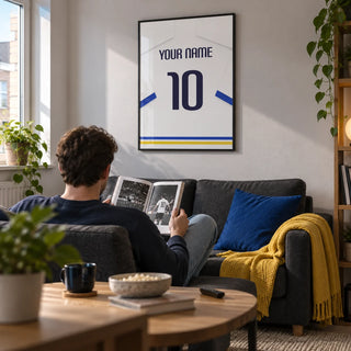 Football Shirt Poster in White with Blue Sleeves and Black Number, framed on the wall of a contemporary football-watching snug in a young adult's UK first flat (22-28) with a pale grey wall in a living room