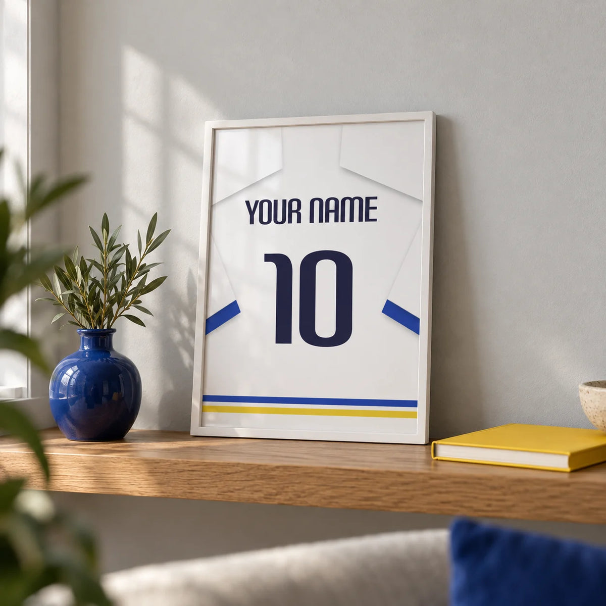 Football Shirt Poster in White with Blue Sleeves and Black Number, a small A4 framed print leaning on an oak shelf in a living room