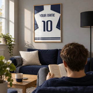 Football Shirt Poster in White with Navy Sleeves and Navy Number, framed on the wall of a contemporary football fan's snug in a UK first flat (22-28) with a soft grey wall in a living room