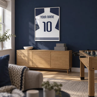 Football Shirt Poster in White with Navy Sleeves and Navy Number, framed on the wall of a neat games room in a UK family home with a navy feature wall and light oak flooring in a living room