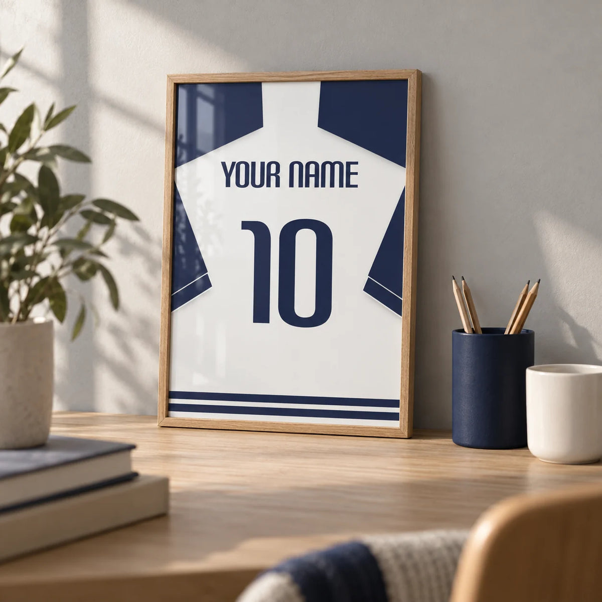 Football Shirt Poster in White with Navy Sleeves and Navy Number, a small A4 framed print leaning on a pale oak desk